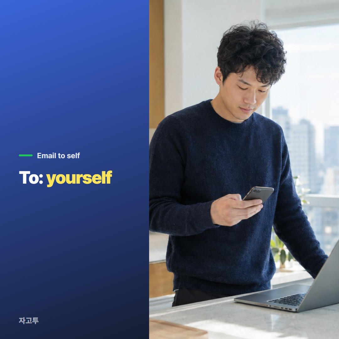 A man at a kitchen counter checking his phone next to an open laptop